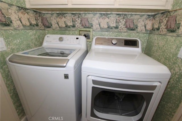 washroom featuring wallpapered walls, cabinet space, and washing machine and clothes dryer