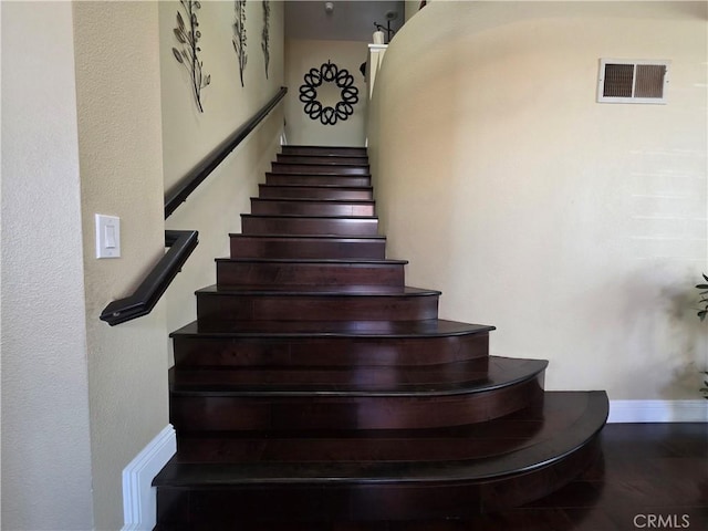 staircase with visible vents and baseboards