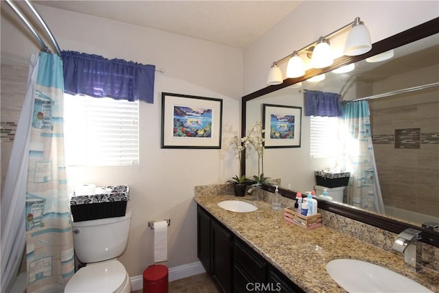 bathroom with baseboards, a sink, toilet, and double vanity