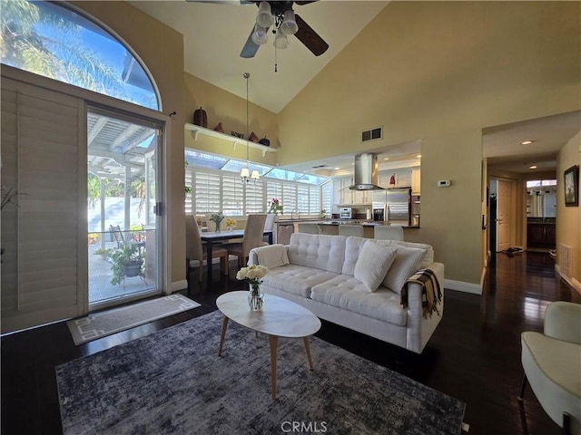 living room with high vaulted ceiling, a wealth of natural light, visible vents, and baseboards