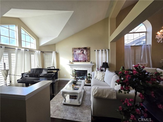 living area with high vaulted ceiling, dark wood-style flooring, a brick fireplace, and a wealth of natural light