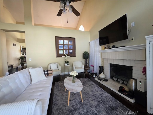 living room with high vaulted ceiling, wood finished floors, visible vents, a ceiling fan, and a brick fireplace