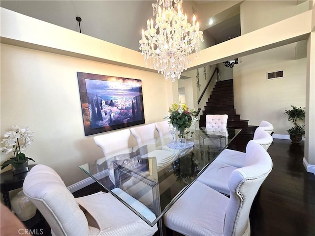 dining room featuring baseboards, visible vents, wood finished floors, an inviting chandelier, and stairs