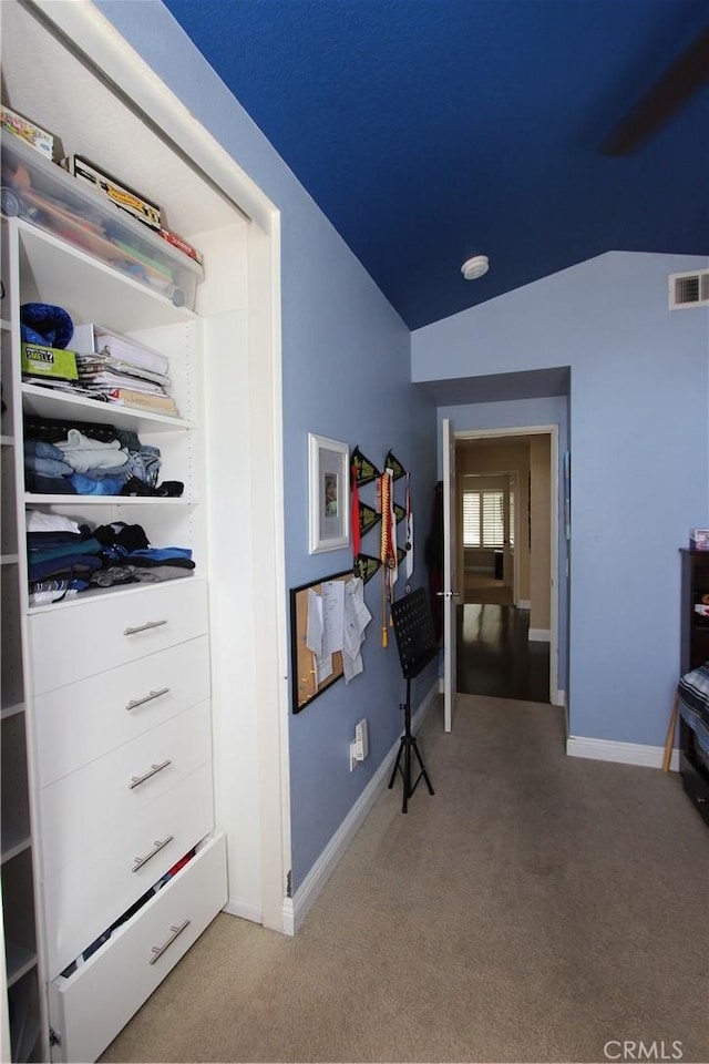 hallway with carpet floors, baseboards, visible vents, and vaulted ceiling