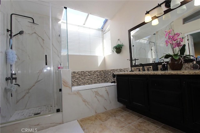 bathroom with tile walls, vanity, a marble finish shower, and a skylight