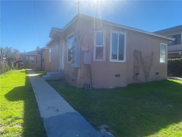 view of side of property featuring crawl space, a lawn, and stucco siding