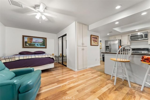 bedroom featuring stainless steel refrigerator with ice dispenser, light wood finished floors, recessed lighting, visible vents, and baseboards