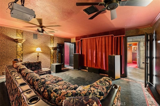 home theater room with visible vents, ornamental molding, ceiling fan, a textured ceiling, and wallpapered walls