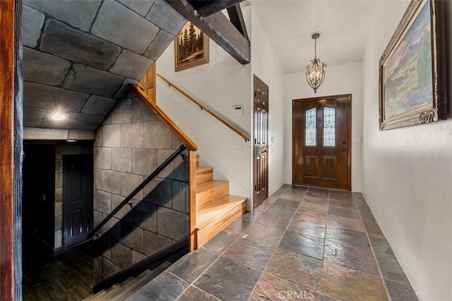 entryway featuring stone tile floors, stairway, and a notable chandelier