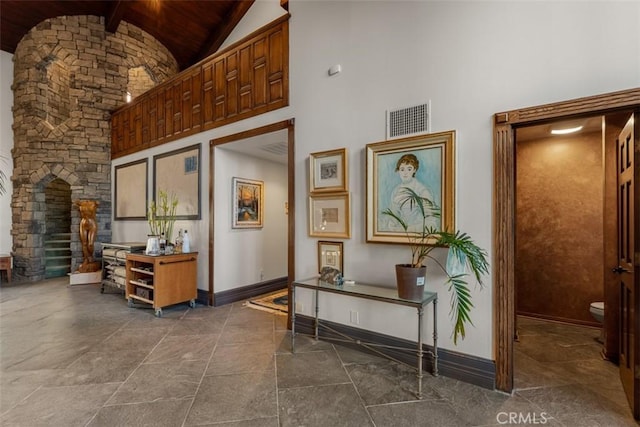 interior space with high vaulted ceiling, wooden ceiling, visible vents, and baseboards