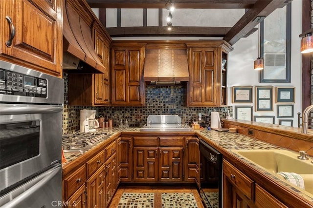 kitchen with stainless steel appliances, a sink, custom exhaust hood, wall chimney exhaust hood, and tasteful backsplash