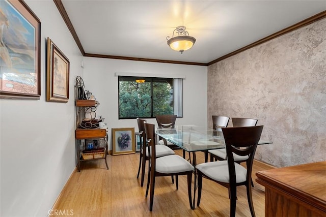 dining room with light wood-style flooring, baseboards, and crown molding