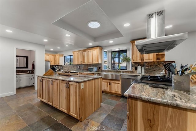 kitchen with island range hood, dishwasher, a kitchen island, a tray ceiling, and a sink