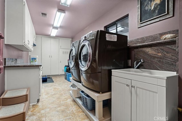 clothes washing area with independent washer and dryer, visible vents, cabinet space, and a sink