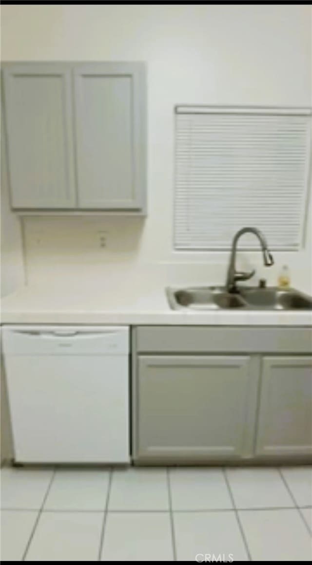 interior space featuring white dishwasher, a sink, and light tile patterned floors