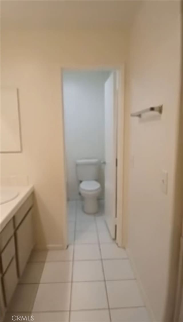 bathroom with toilet, vanity, and tile patterned floors