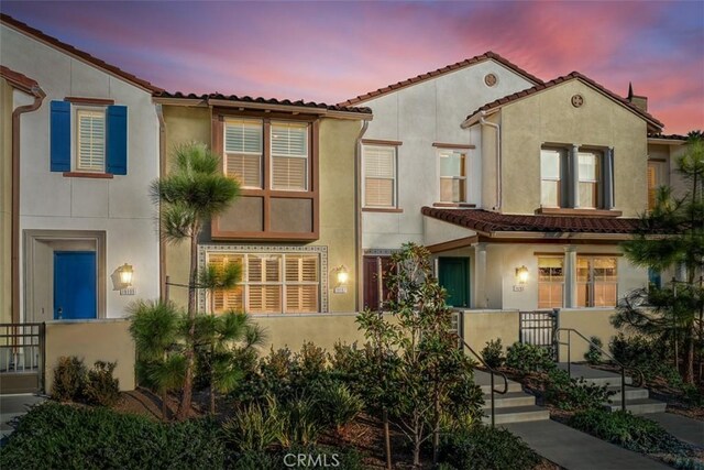 mediterranean / spanish home with a fenced front yard, a tile roof, and stucco siding