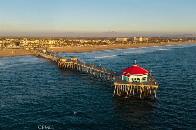 view of dock featuring a pier, a view of the beach, and a water view