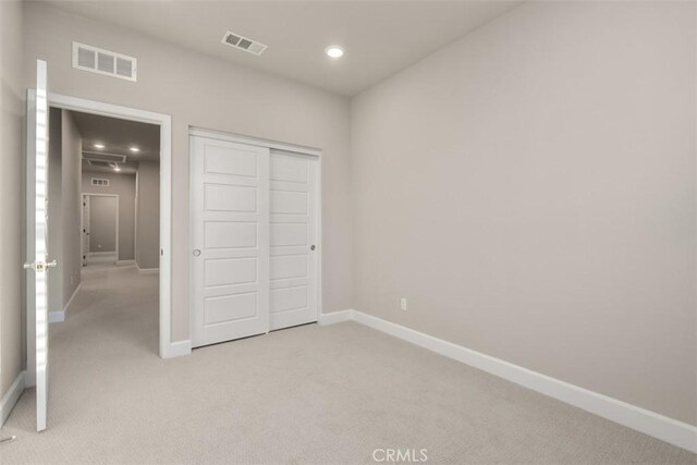 unfurnished bedroom featuring baseboards, visible vents, and light colored carpet