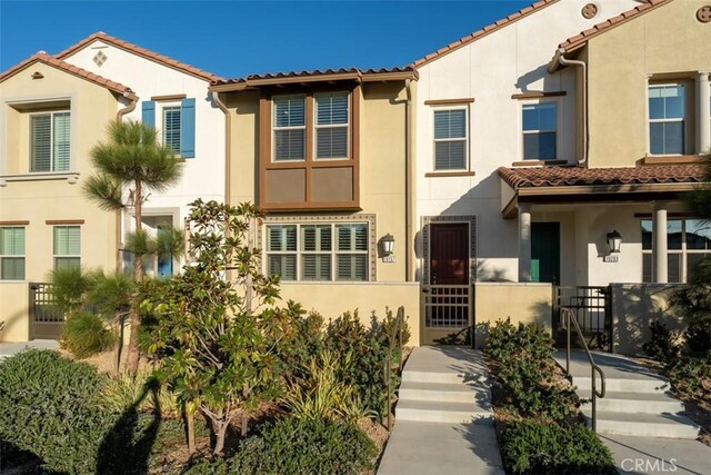 view of front of property with a fenced front yard, a gate, a tiled roof, and stucco siding