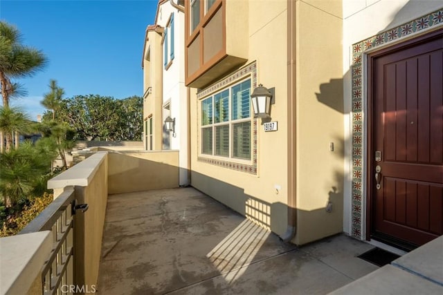 property entrance with a balcony and stucco siding