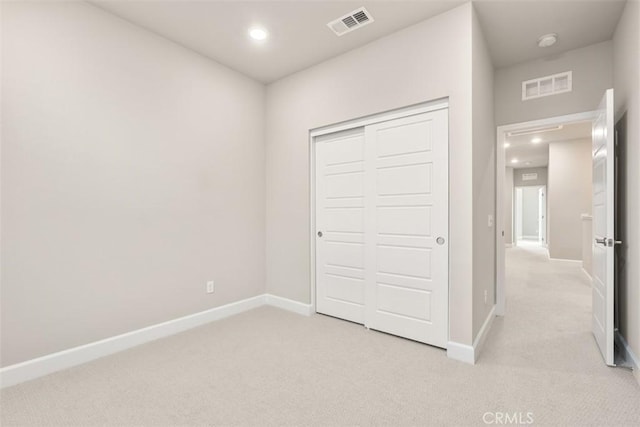 unfurnished bedroom with light carpet, a closet, visible vents, and baseboards