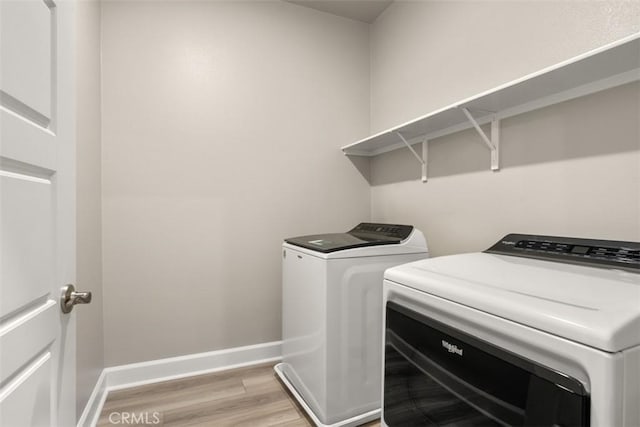 laundry room featuring laundry area, light wood-style flooring, baseboards, and washing machine and clothes dryer