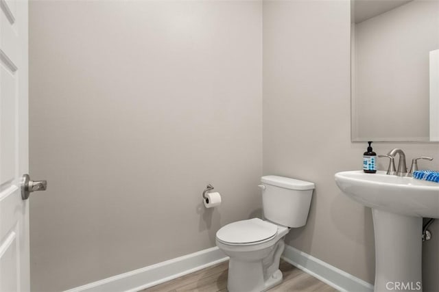 bathroom with baseboards, toilet, and wood finished floors