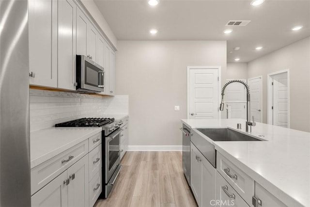 kitchen featuring visible vents, appliances with stainless steel finishes, light countertops, white cabinetry, and backsplash