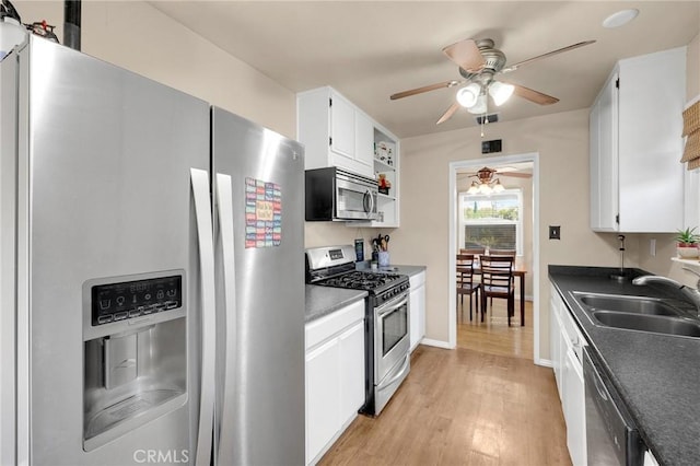 kitchen featuring appliances with stainless steel finishes, dark countertops, white cabinets, and a sink