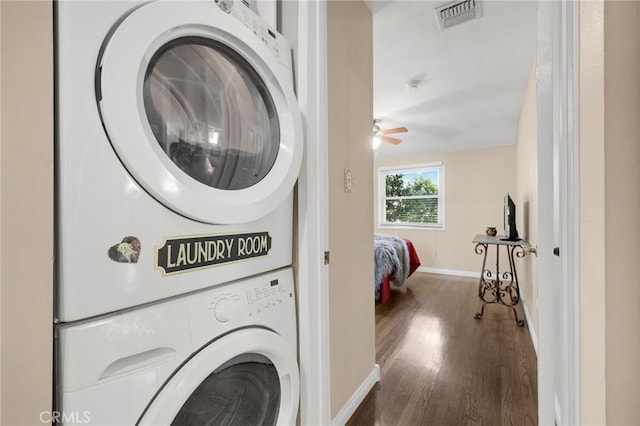 laundry room featuring dark wood-style floors, visible vents, stacked washer / dryer, laundry area, and baseboards