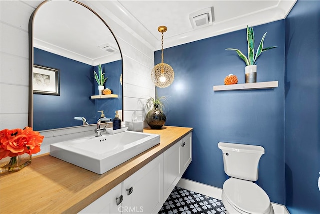 half bath with visible vents, toilet, vanity, and baseboards