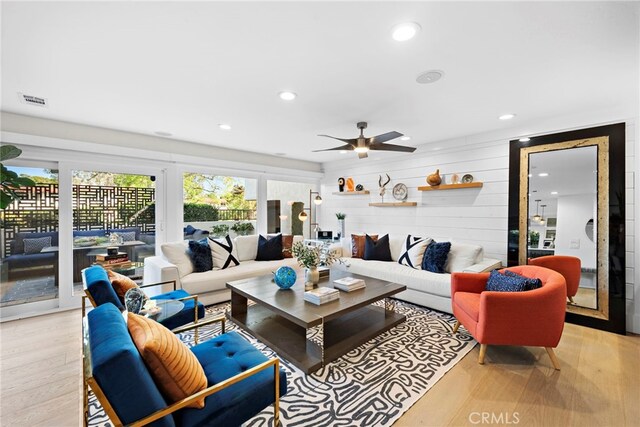 living room featuring visible vents, wooden walls, recessed lighting, and light wood-type flooring