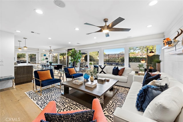 living area featuring ceiling fan with notable chandelier, recessed lighting, light wood-style floors, and visible vents