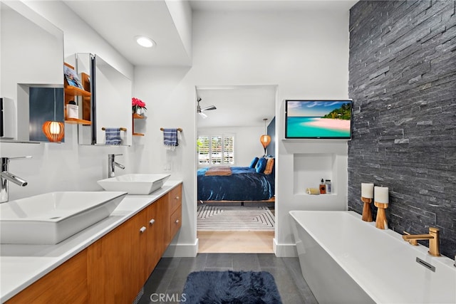 ensuite bathroom featuring double vanity, a freestanding tub, ensuite bath, and a sink