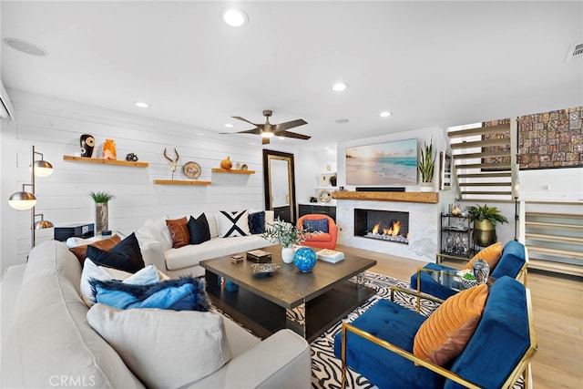 living room featuring recessed lighting, wood finished floors, and a warm lit fireplace