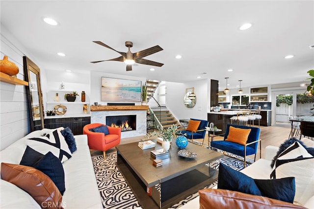 living room with stairway, recessed lighting, a lit fireplace, and ceiling fan