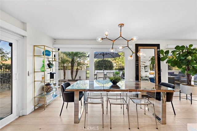 dining space with a healthy amount of sunlight, light wood-type flooring, and a chandelier