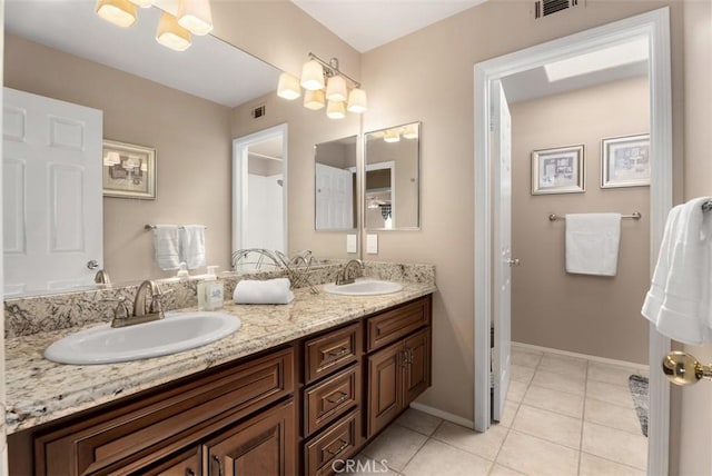 full bathroom featuring double vanity, tile patterned flooring, baseboards, and a sink