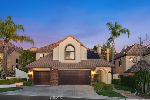 mediterranean / spanish-style house featuring a garage, a tile roof, driveway, and stucco siding