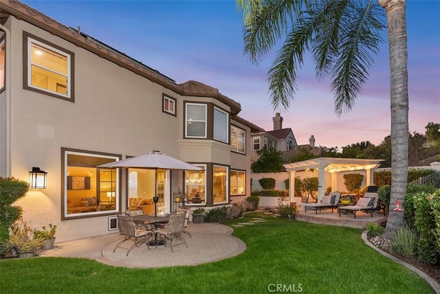 back of property featuring a yard, stucco siding, a patio, and a pergola