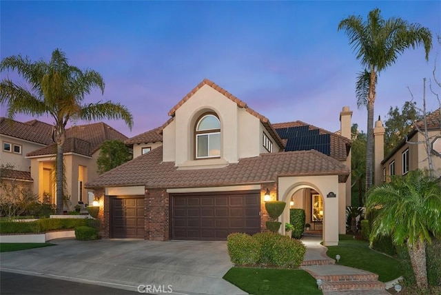 mediterranean / spanish house with driveway, a tile roof, and stucco siding