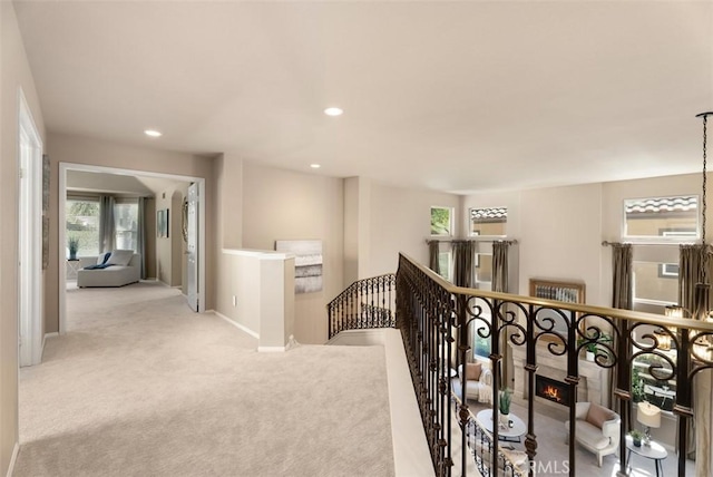 hallway featuring baseboards, carpet floors, an upstairs landing, and recessed lighting