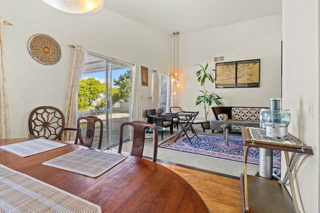 dining room with a towering ceiling, visible vents, and wood finished floors