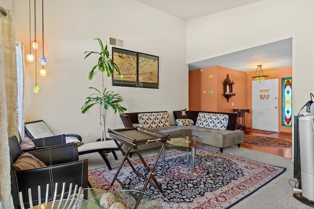 living area featuring carpet floors, a towering ceiling, and visible vents