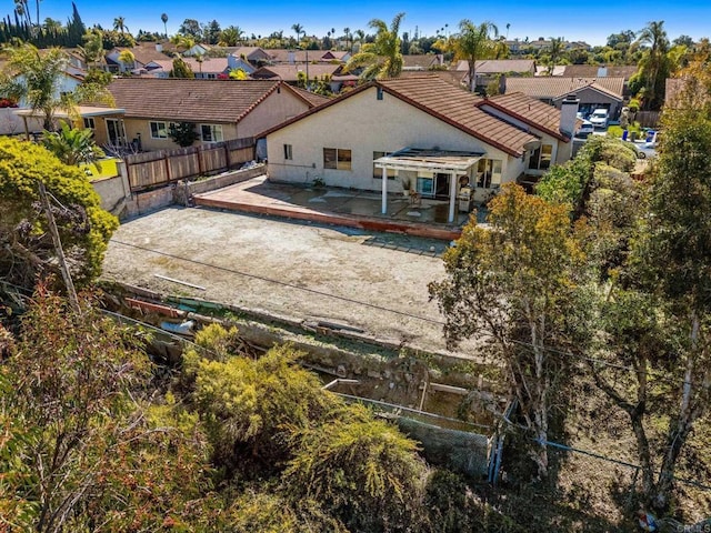 rear view of property featuring a tiled roof, a residential view, fence, and a patio