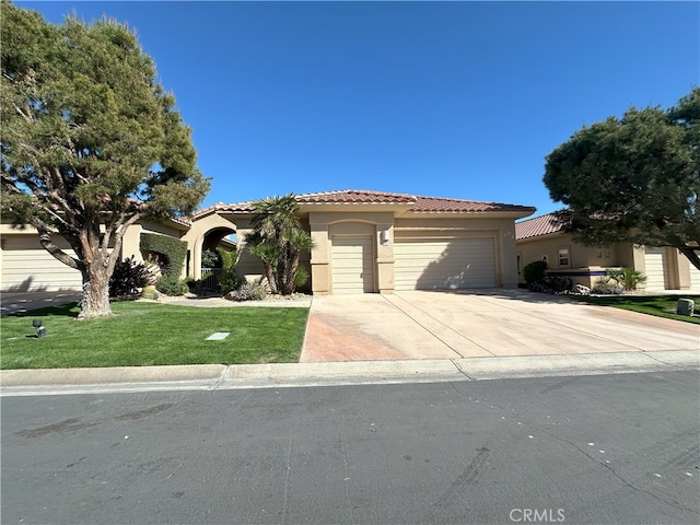 mediterranean / spanish-style home featuring driveway, a tiled roof, an attached garage, and stucco siding