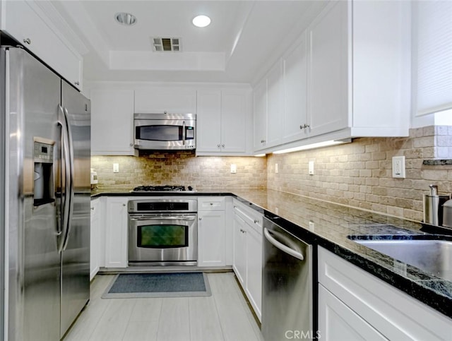 7249 Franklin Ave Unit 205, Hollywood Hills, CA 90046 - kitchen with stainless steel appliances, white cabinetry, a raised ceiling, a sink, and dark stone counters