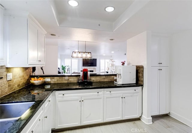 7249 Franklin Ave Unit 205, Hollywood Hills, CA 90046 - kitchen with a raised ceiling, backsplash, white cabinetry, a peninsula, and recessed lighting