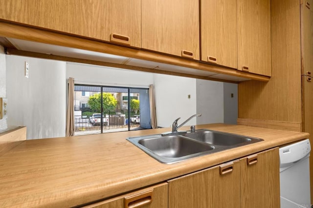 kitchen featuring light countertops, a sink, and white dishwasher